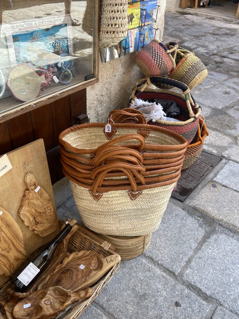 The outside of a shop in Corsica, France that has displayed handwoven wicker baskets and wooden carvings.