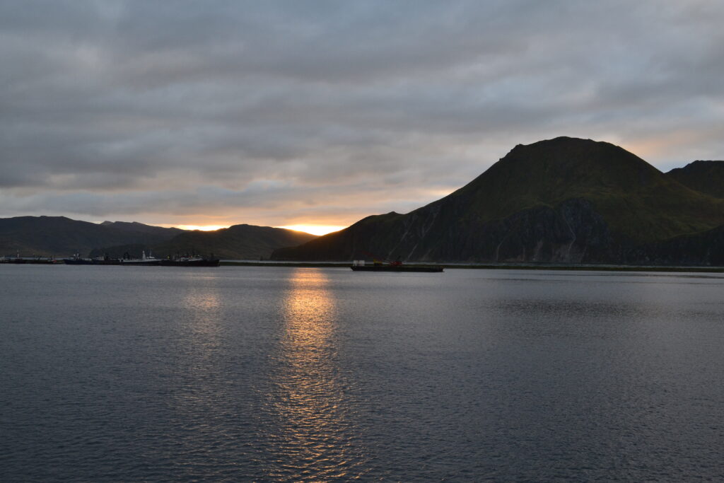 Sun setting behind mountains over bay in Unalaska