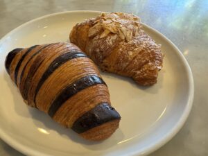 Almond croissant and black sesame croissant next to each other on a plate