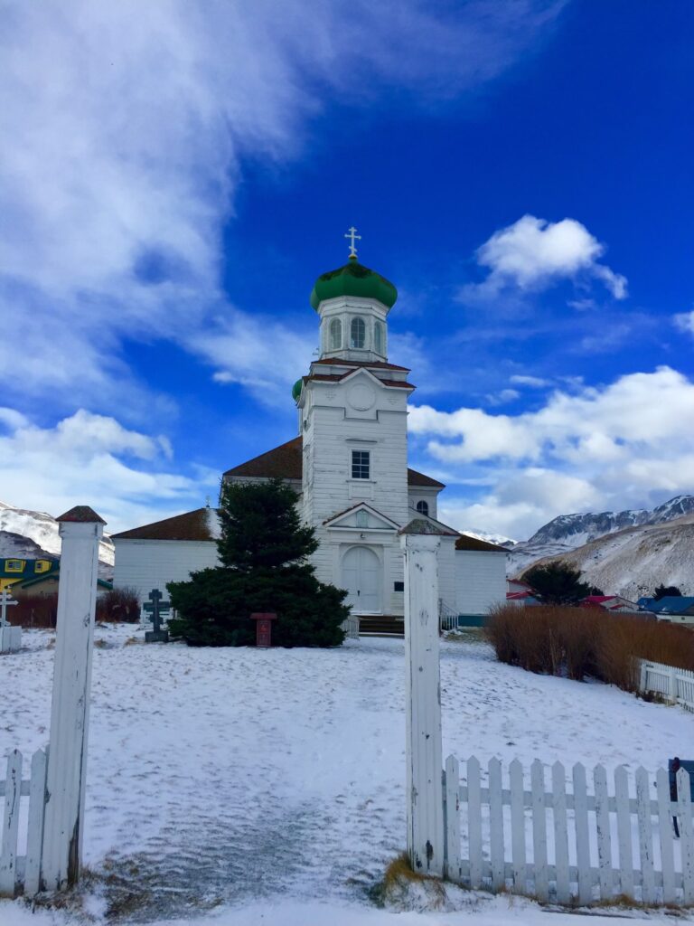 Orthodox church on a little hill in the snow with white picket fence