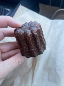 A hand holding a French canele pastry