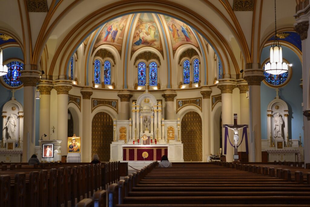 Catholic church altar with the exposition of the Holy Eucharist under a dome that has paintings of the Joyful Mysteries of the rosary