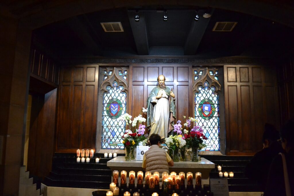 Shrine of Saint Jude with stained glass windows on either side and votive candles