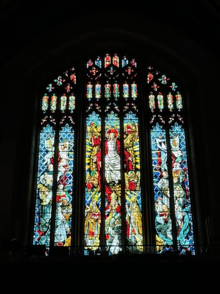 A stained glass window representing Christ with the four evangelists, three popes and saints in heaven.