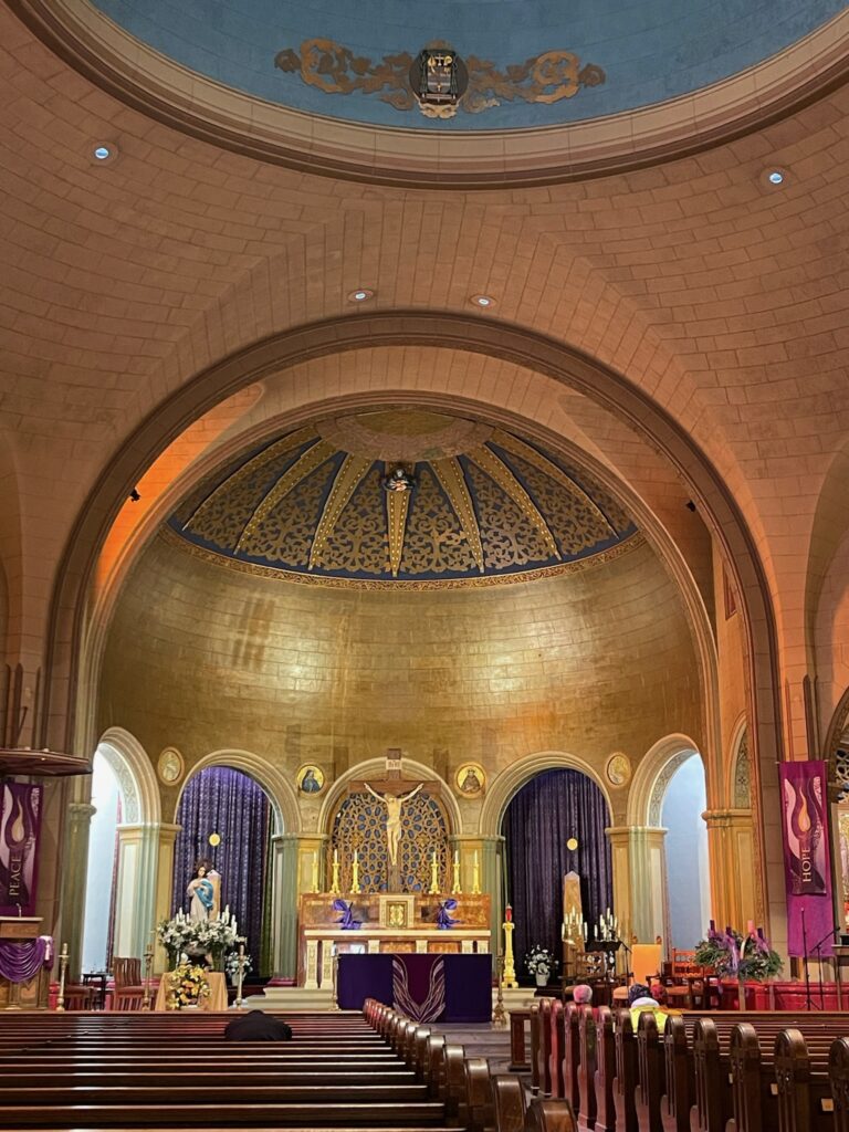 Inside of a church in San Francisco with a curved golden dome above the altar
