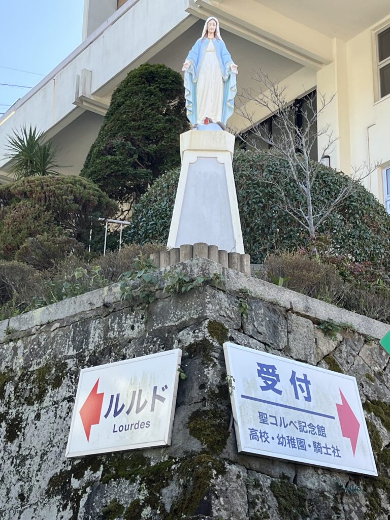 A statue of Mary on a wall with two signs under her
