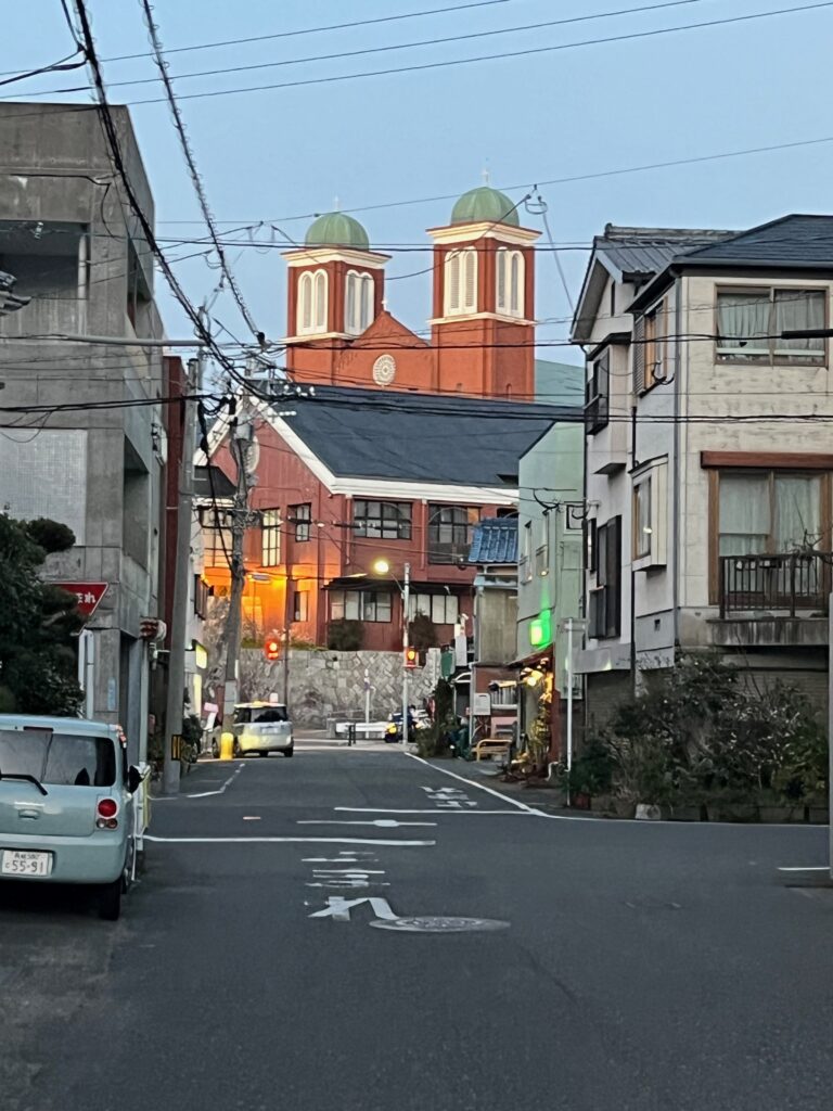 A city street leads to a brick church with two spires