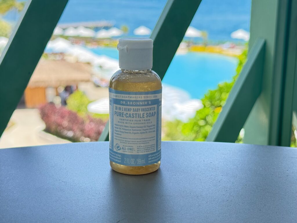 Mini bottle of castile soap on a table with pool in the background