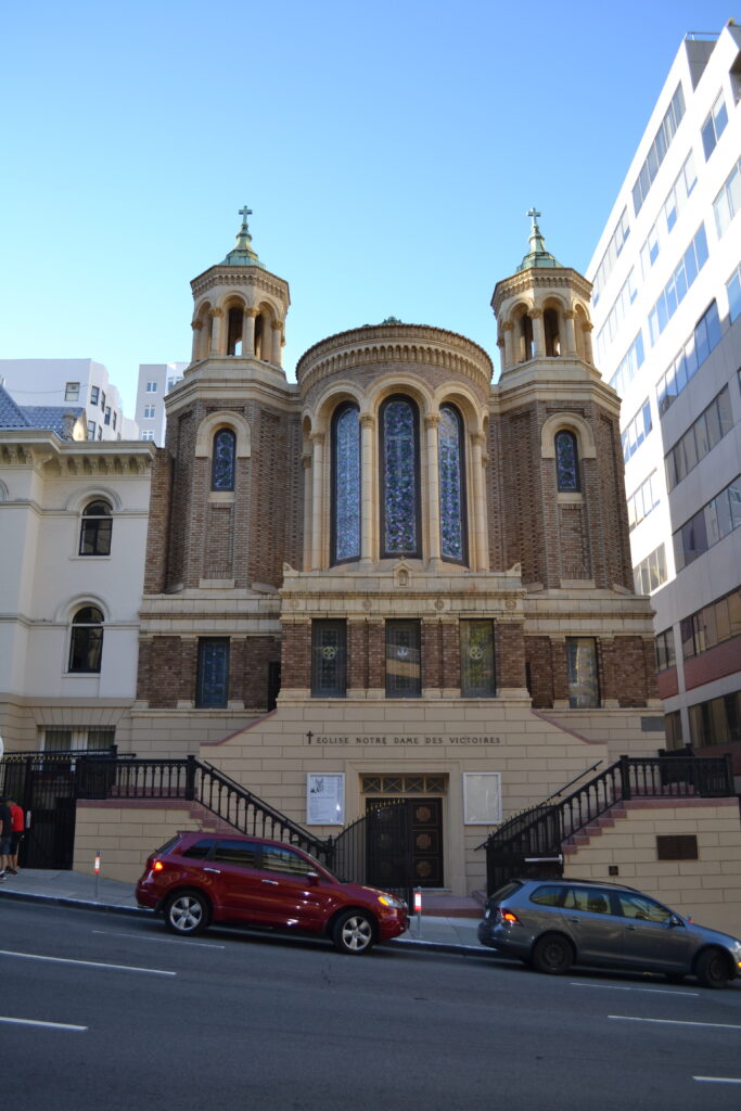 Across a hilly street, a double staircase leads up the apse of a church flanked by two towers