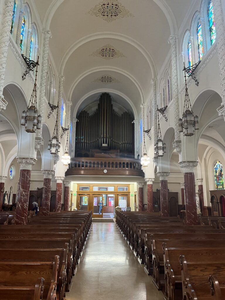 Pews and marble columns line the way to the back of the church and an organ above