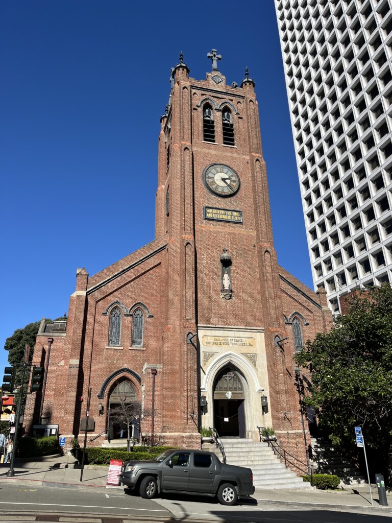 A brick church facade with one tower and a clock