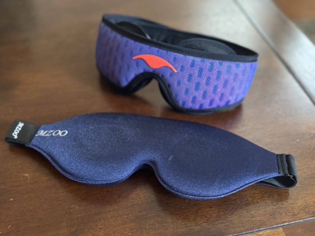 A purple sleep mask and blue sleep mask on a wooden table