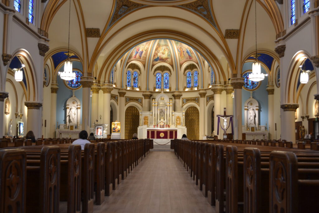 Pews along a path lead to an altar under a beautiful apse