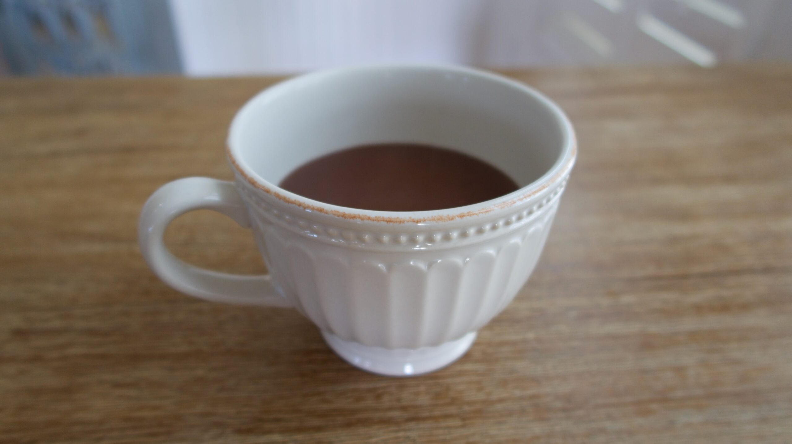 an ivory mug with thick french hot chocolate inside on a table