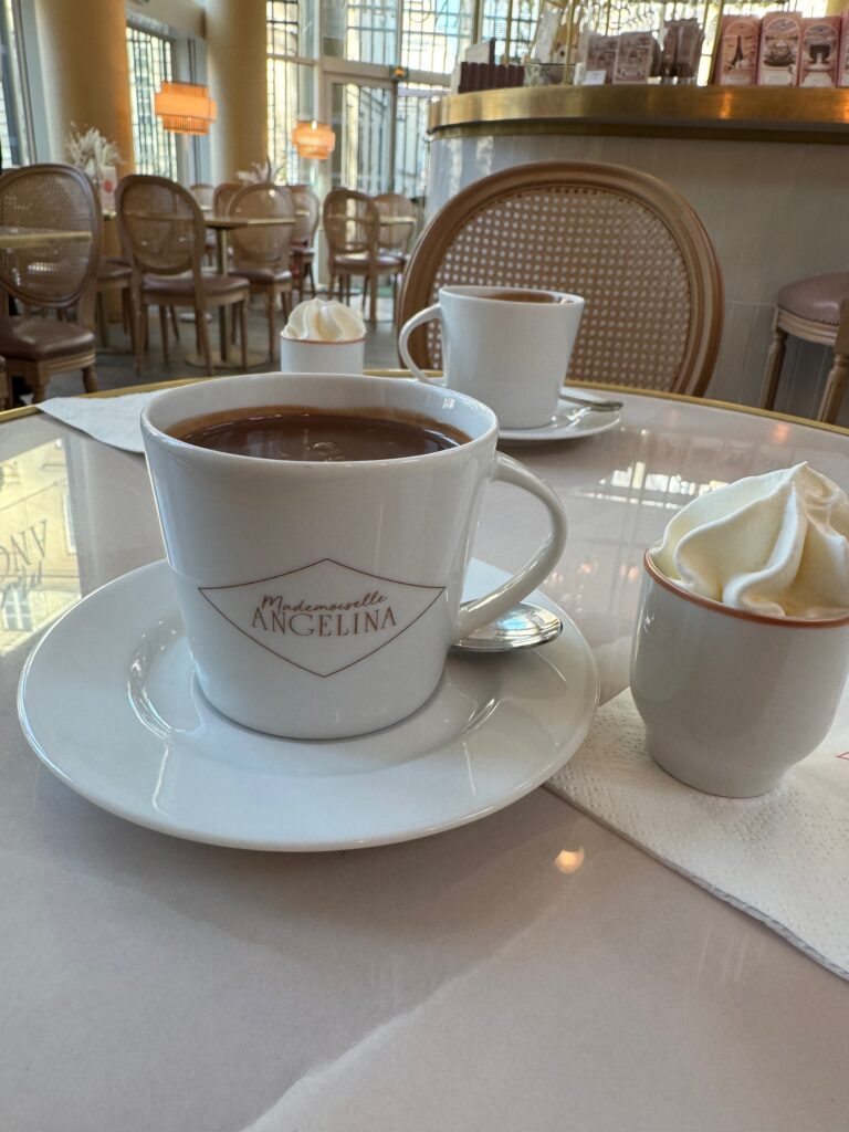 Mugs of French hot chocolate on a table with the rest of the cafe in the backfround