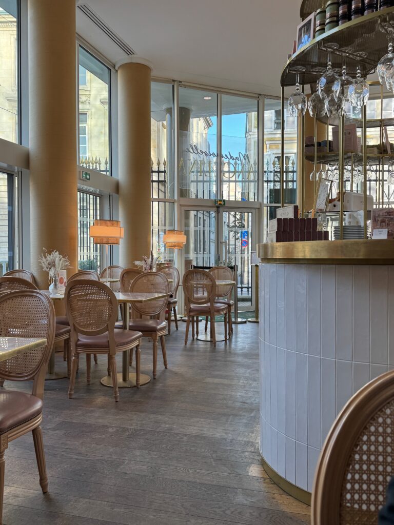 Parisian cafe with floor to ceiling windows and a coffee and wine bar on the right