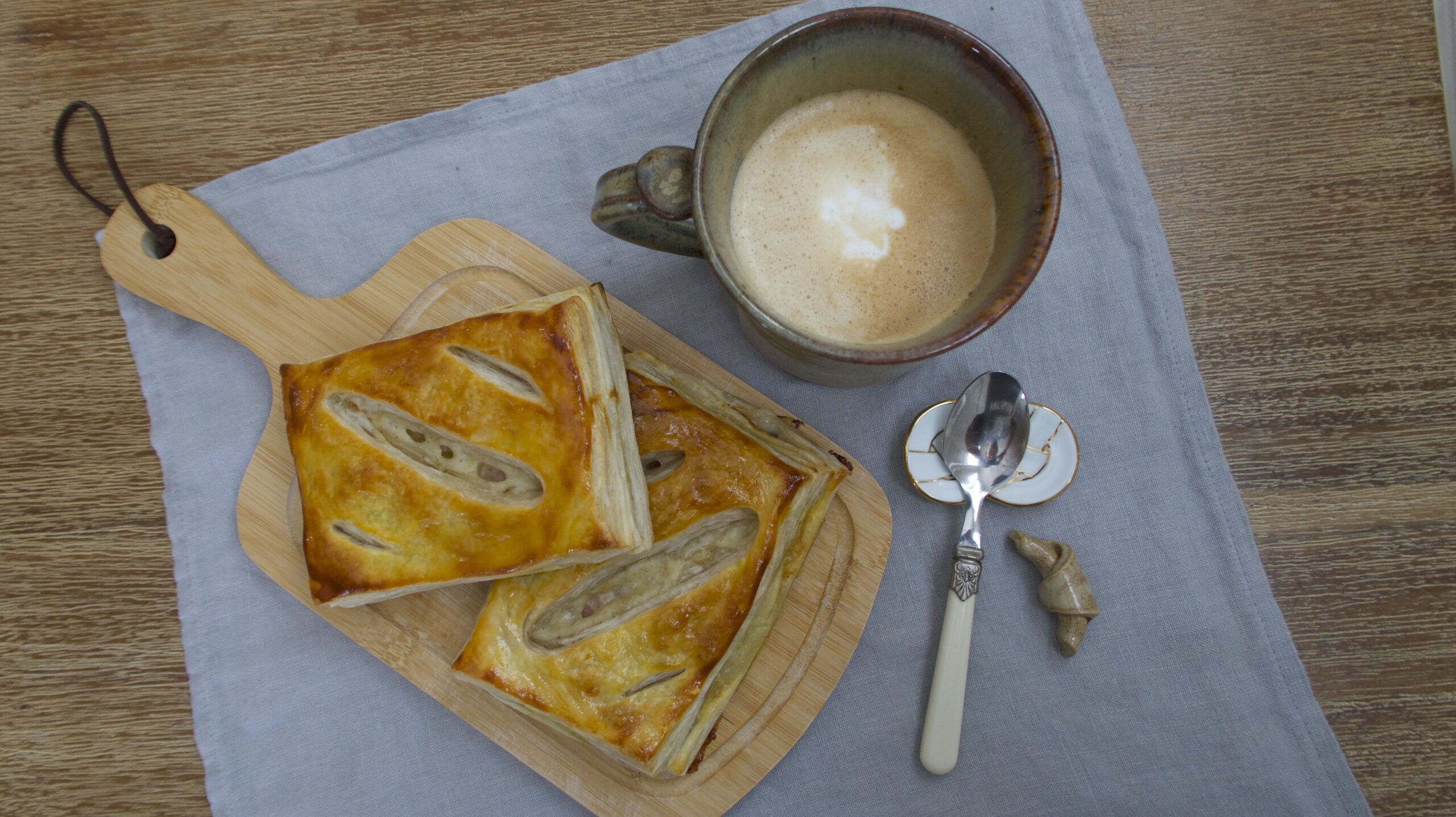 Puff Pastries, coffee, and utensils on a linen napkin on a wooden table