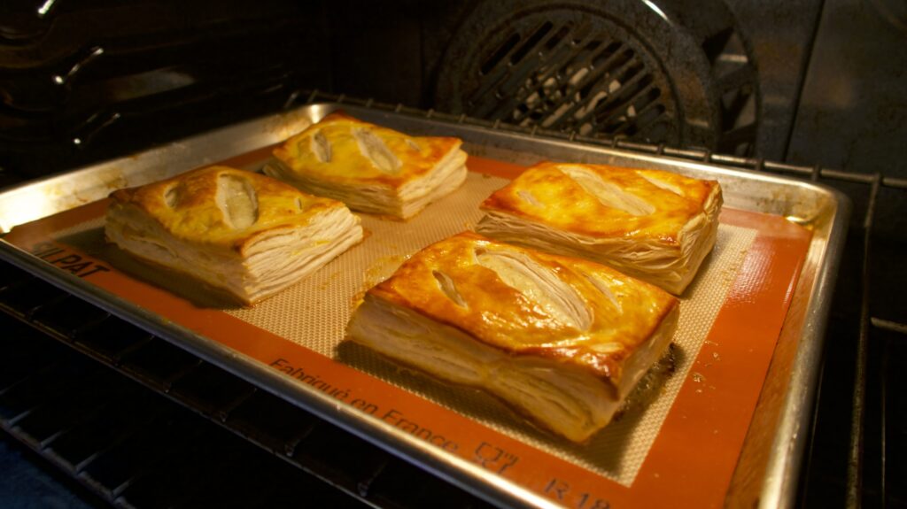 Puff pastries being baked inside an oven on a baking tray