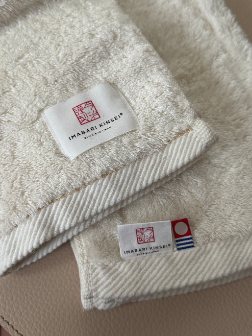 Two cotton towels folded with a logo and special iconic tag on its edges
