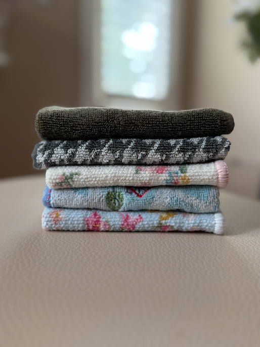 A stack of folded hand towels in various colors and designs