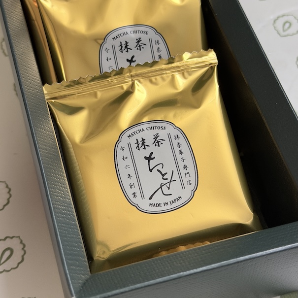 Individually wrapped Matcha Chitose cookies in elegant gold foil packaging inside a dark gift box. The white label features Japanese calligraphy and "Made in Japan" text.