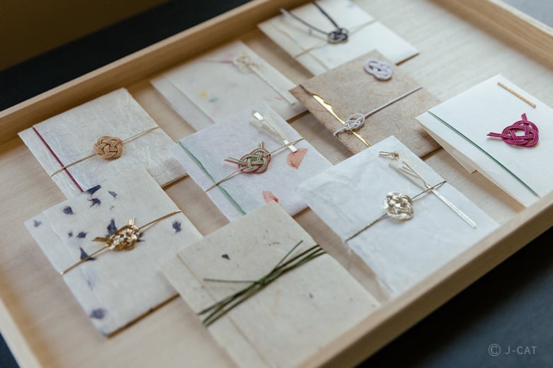 Traditional Japanese mizuhiki knot designs on handmade paper envelopes, decorative gift wrapping and cultural craft experience
