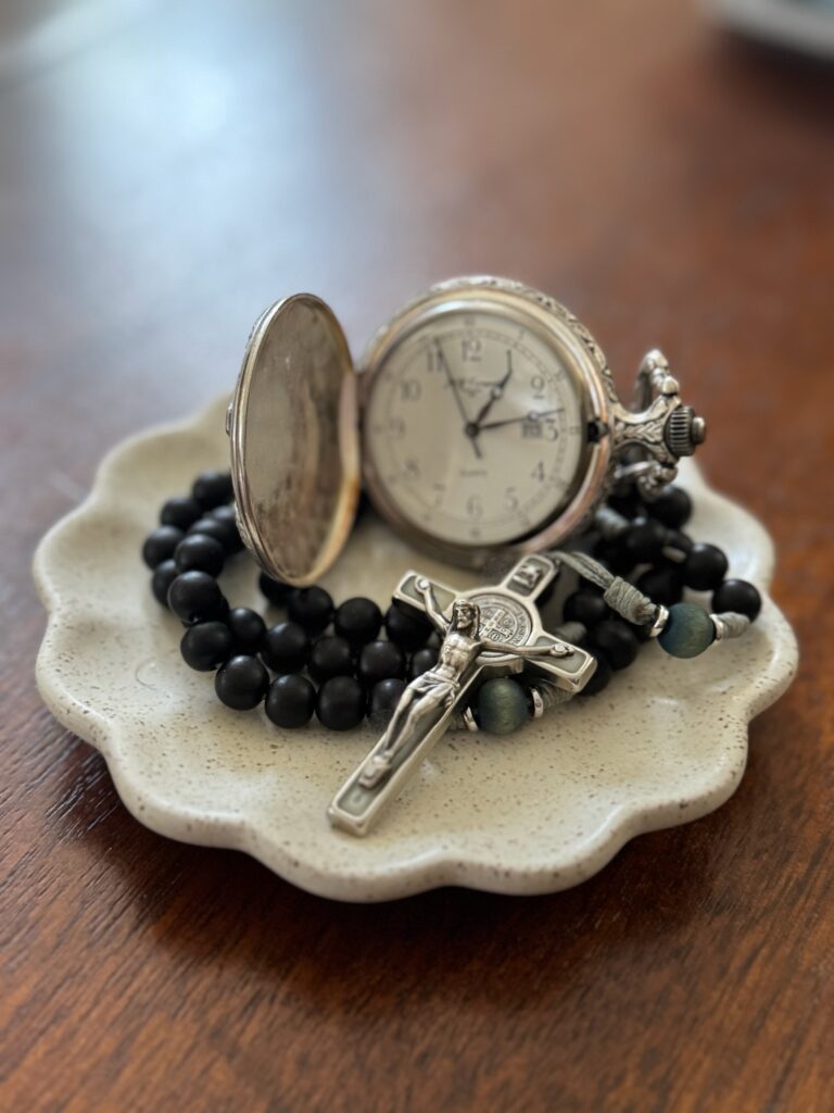 Pocket watch and a rosary on a little scalloped dish