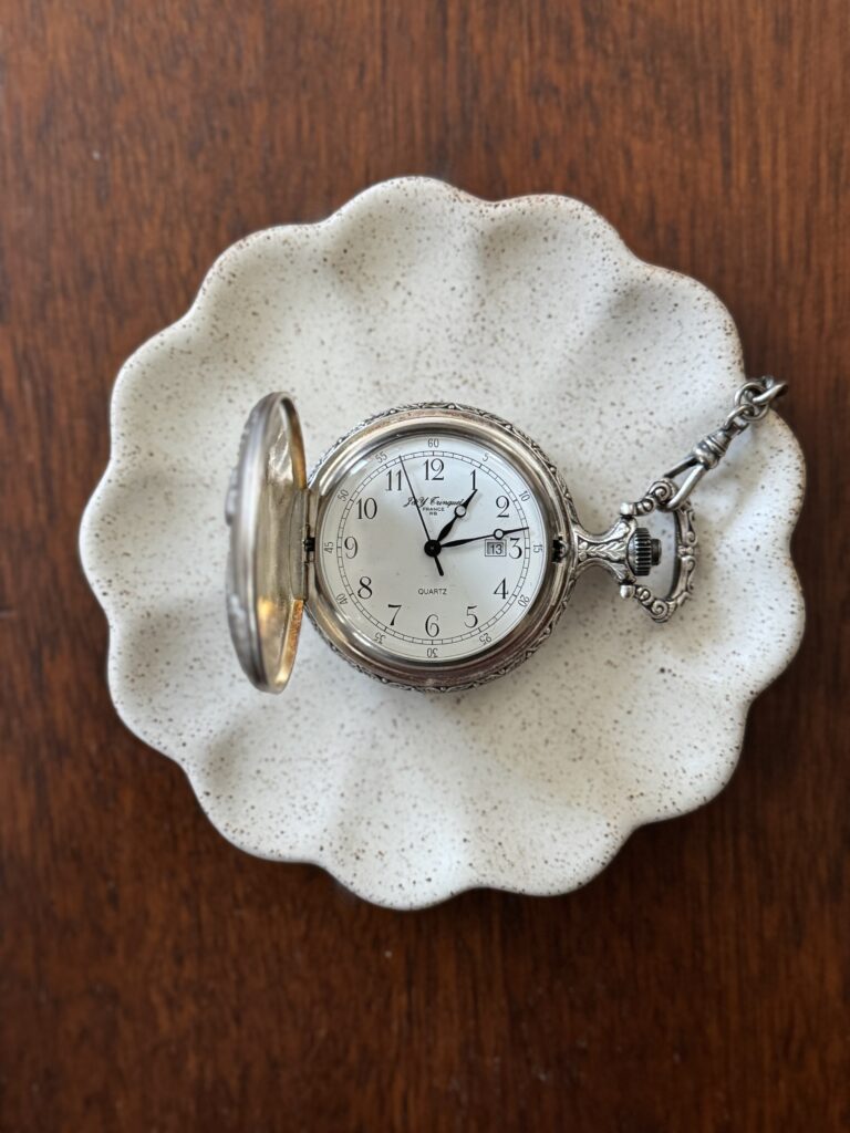 Silver pocket watch on a scalloped trinket dish