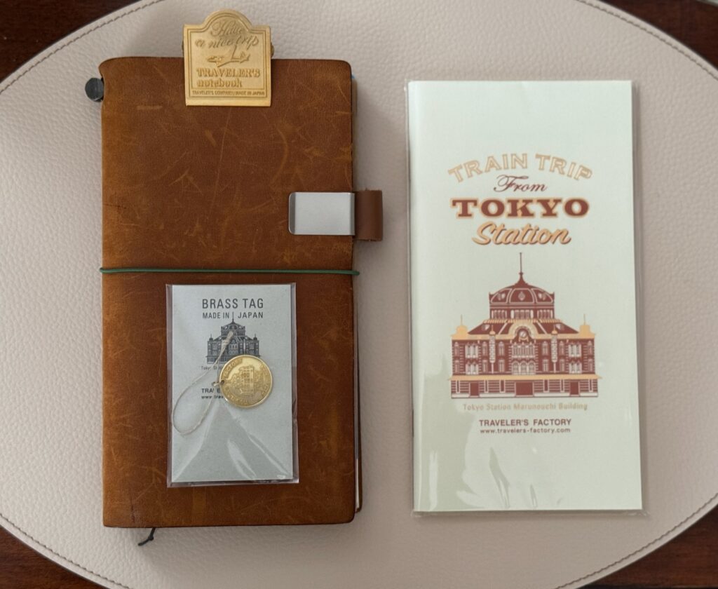 Leather notebook next to a notebook insert that has Tokyo Station on the cover
