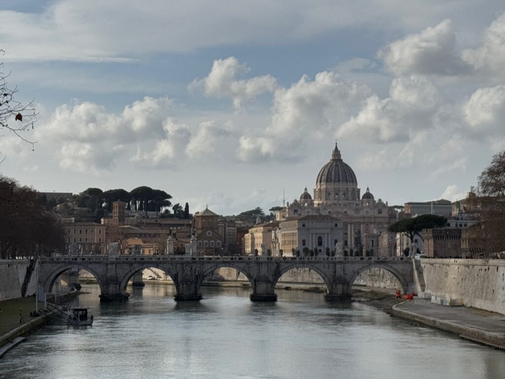 Picture of basilica in the back with a bridge over a river in the front