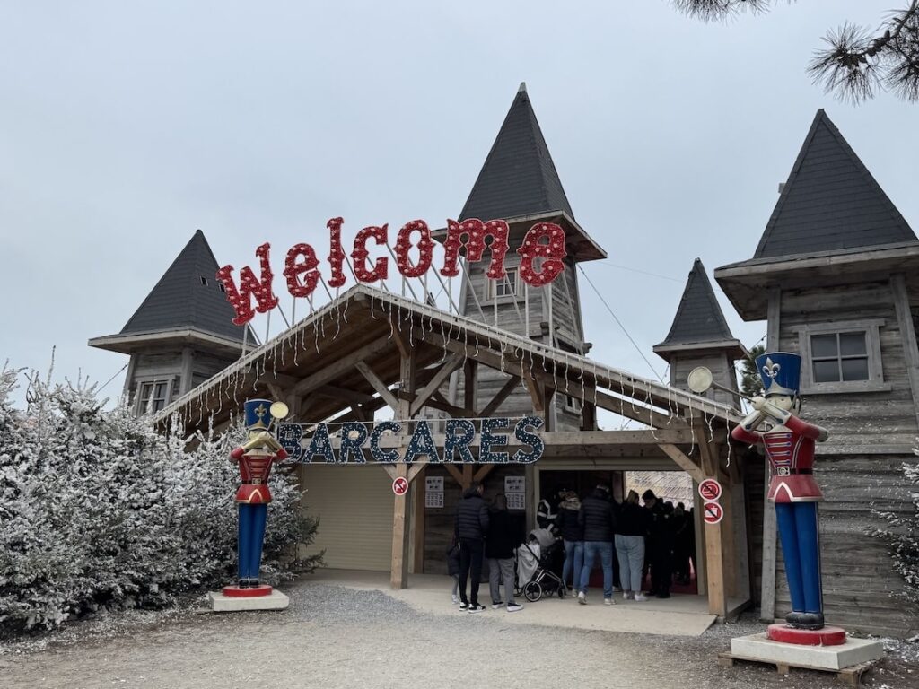Entrance to a Christmas village in France with welcome sign and life-sized wooden nutcrackers on either side of the entrance