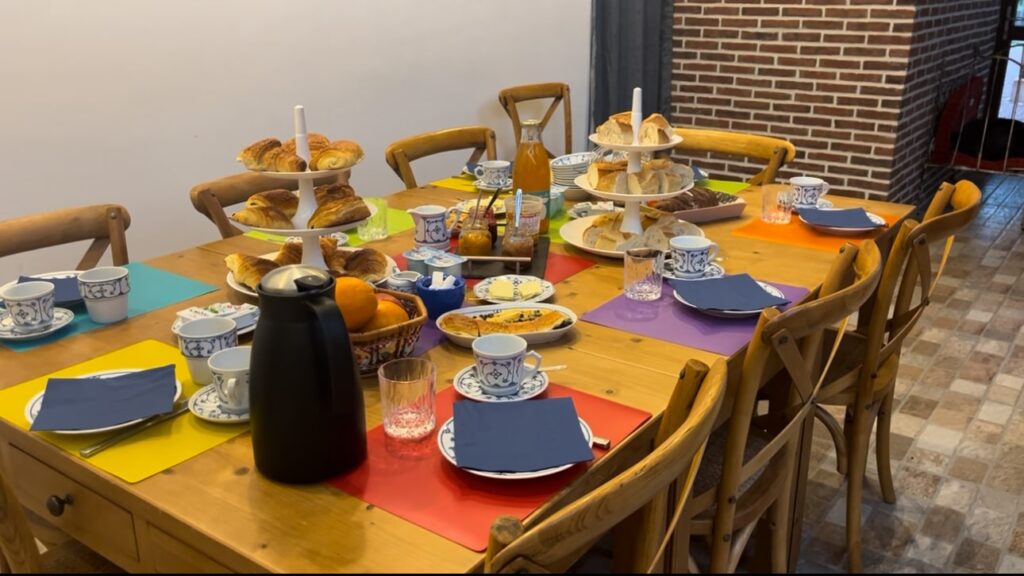 French breakfast spread on a wooden dining table with fruits and pastries