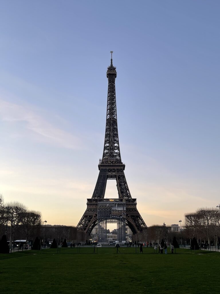 Eiffel tower at sunset with barren trees along the bottom