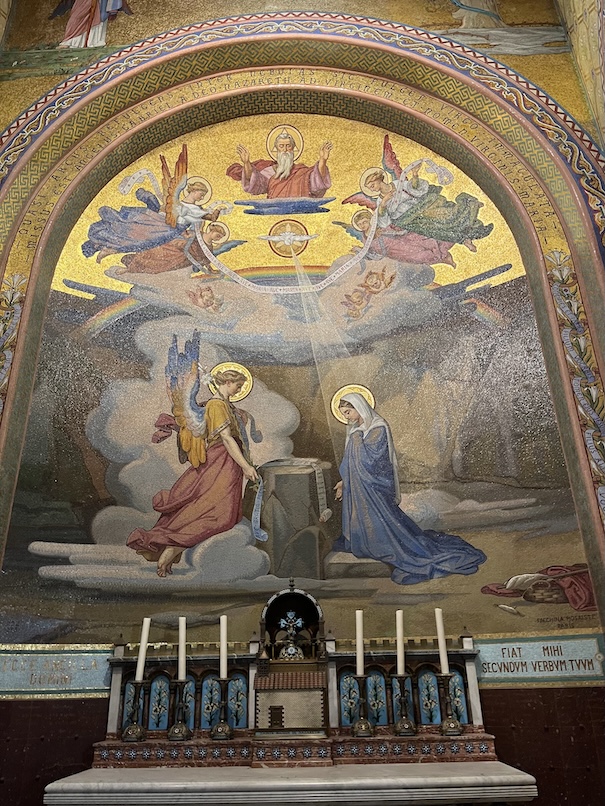 A small side chapel in Lourdes, France with a mosaic art of the Annunciation behind the altar