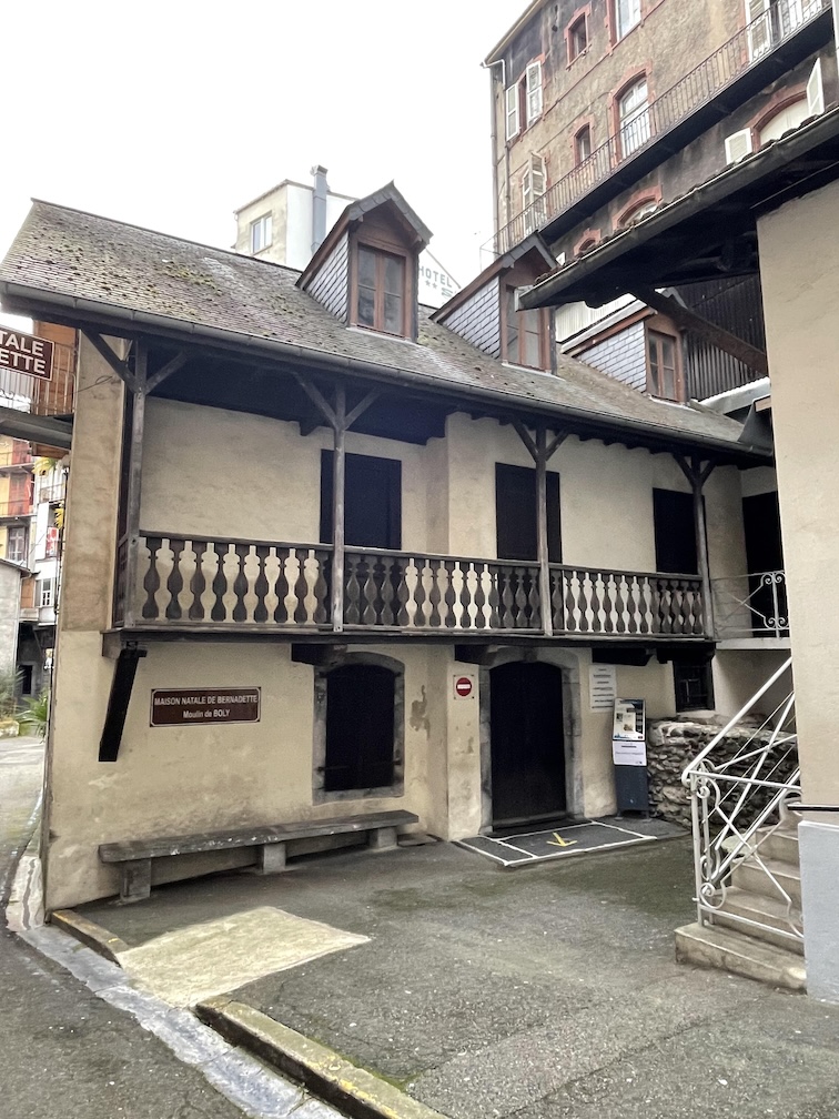 An old French mill in the mountains of Lourdes, France where St. Bernadette was born into the Soubirous family. It is two stories tall is a white building with dark brown shutters