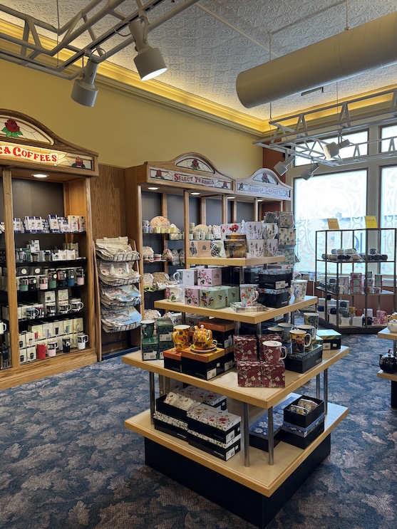 The inside of a store selling tea ware with mugs displayed in the middle of the floor and teas and coffee in the shelves along the wall.
