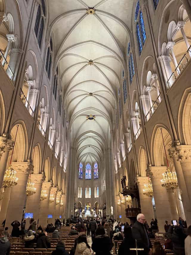 Interior of newly renovated and restored Notre Dame Cathedral with sparkling white vaulted ceilings and stone archways