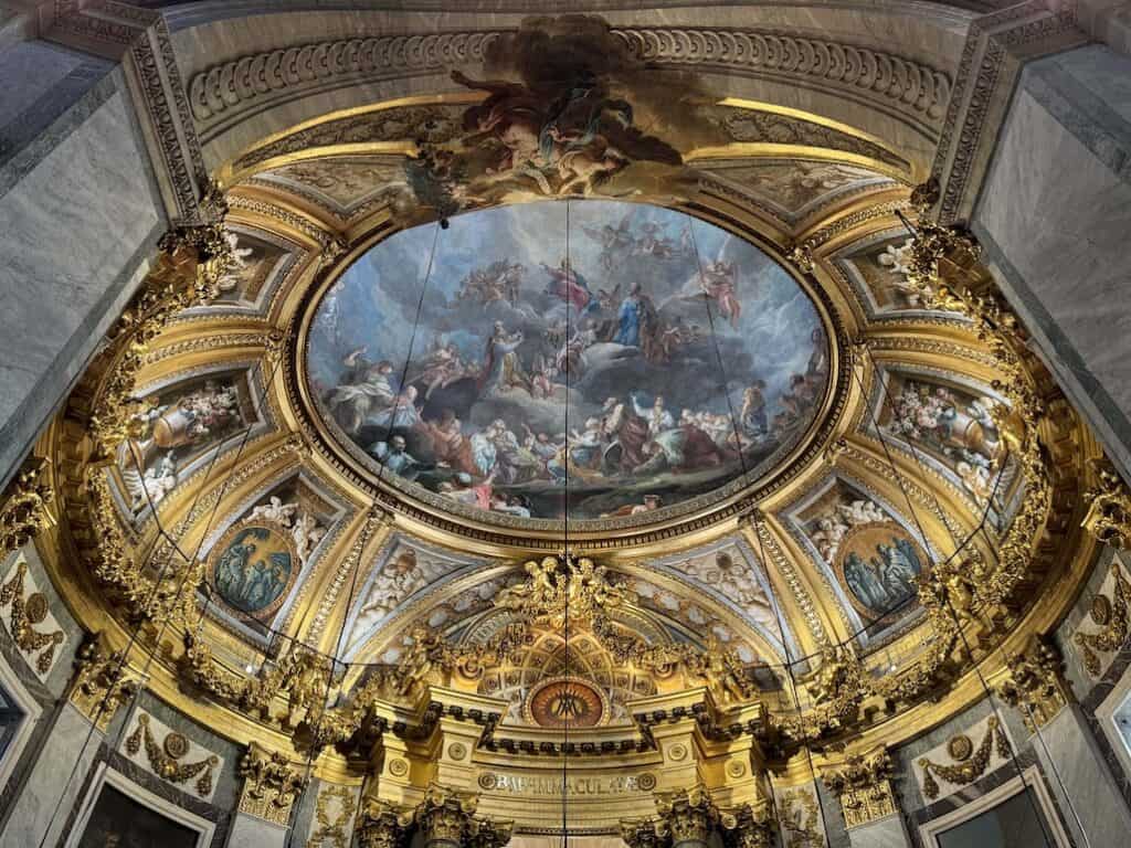 Baroque interior of Chapel of Our Lady inside St Sulpice featuring a domed ceiling with a fresco of the Assumption of Mary by François Lemoyne, lit by natural light from concealed windows.