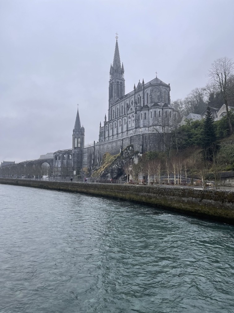 The back view of the Sanctuary of Our Lady of Lourdes taken from across the river on a gloomy and foggy day