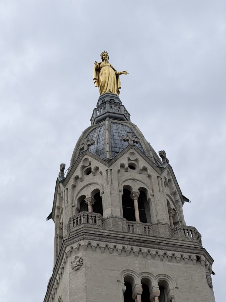 Golden statue of the Virgin Mary atop the Basilica of Notre-Dame de Fourvière tower overlooking Lyon, France.
