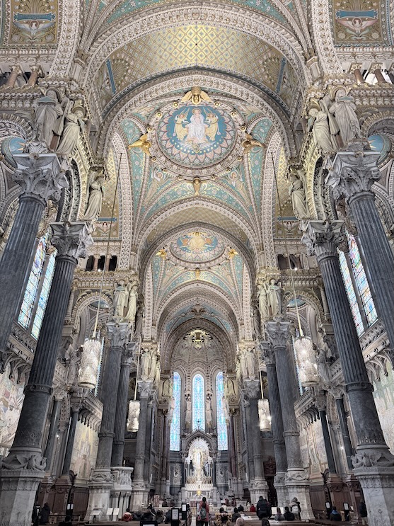 Interior of the Basilica of Notre-Dame de Fourvière in Lyon with ornate mosaics, columns, and vaulted ceilings.