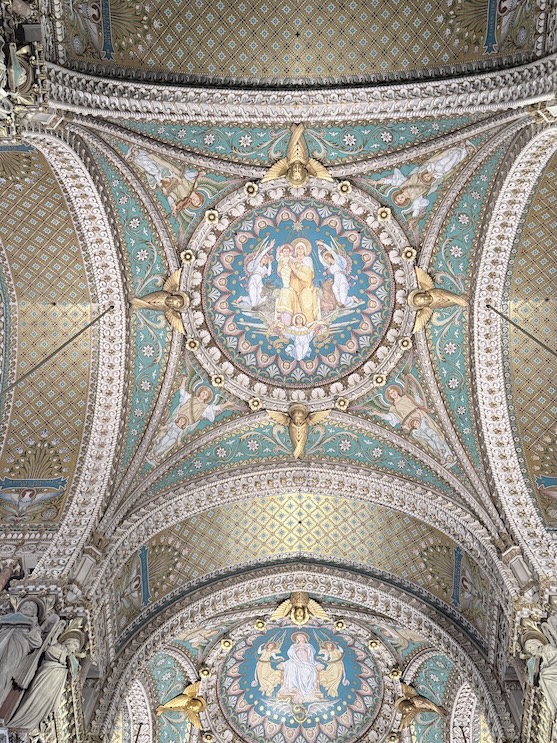 Ornate mosaic ceiling with religious artwork inside the Basilica of Notre-Dame de Fourvière in Lyon, France.