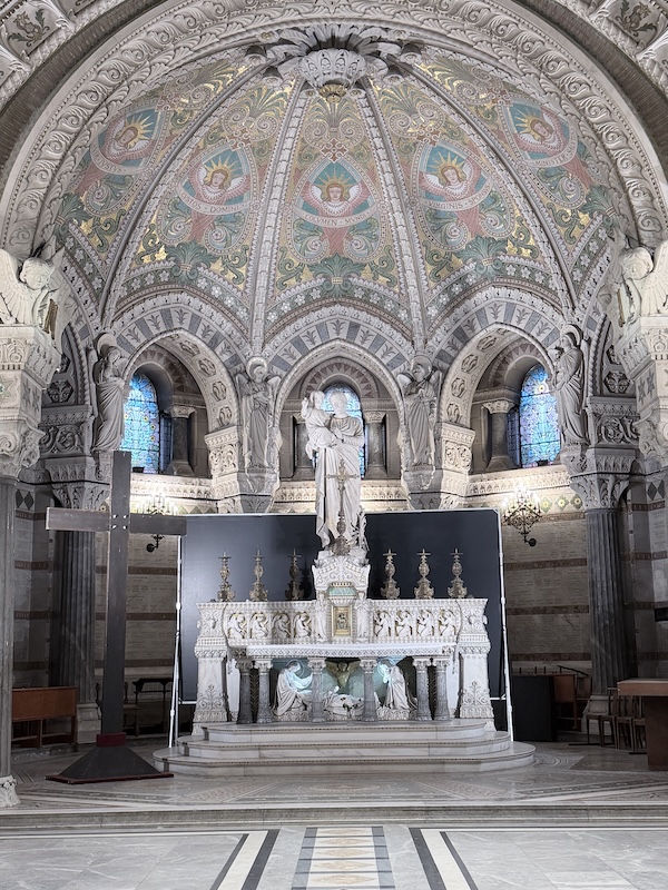 Decorated altar with the statue of St. Joseph holding Jesus in the center and mosaics inside the crypt of the Basilica of Notre-Dame de Fourvière, a historic church in Lyon, France.