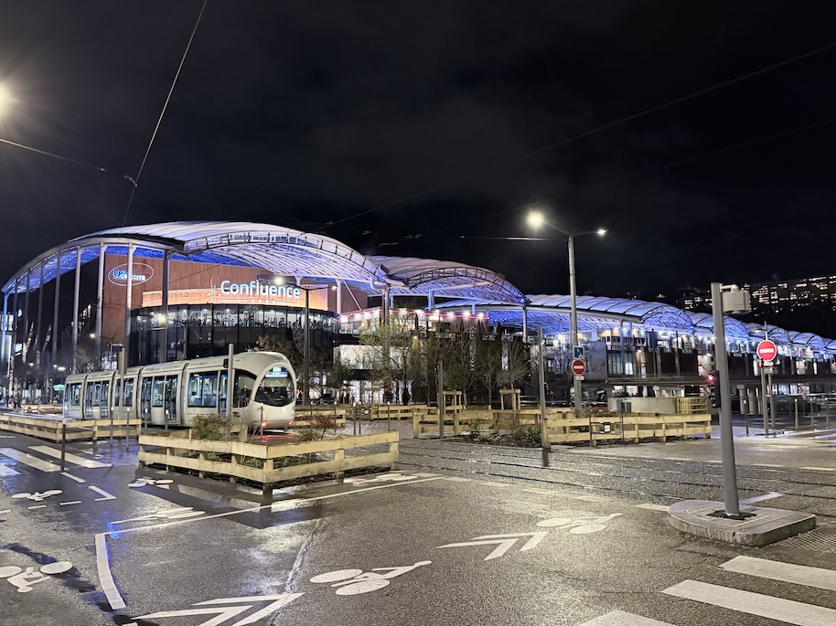 Lyon Confluence shopping and transport hub illuminated at night with modern architecture and tram
