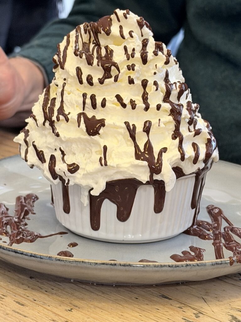 Decadent chocolate fondant dessert topped with whipped cream and melted chocolate at Ikône dessert café Lyon