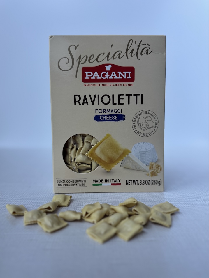 A box of Pagani Ravioletti Formaggi cheese pasta with dried mini ravioli scattered on a clean white surface.