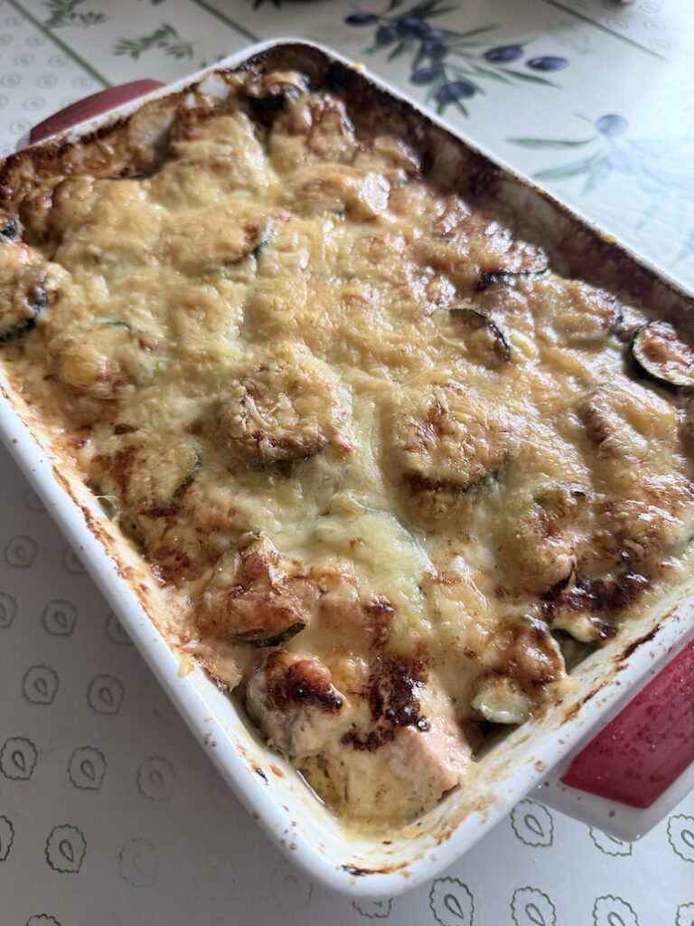 Freshly baked salmon and zucchini gratin casserole featuring a bubbly, golden-brown melted cheese crust.