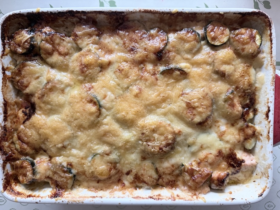 Top-down view of a golden-brown salmon zucchini gratin casserole cooked to a crisp perfection in a baking pan.