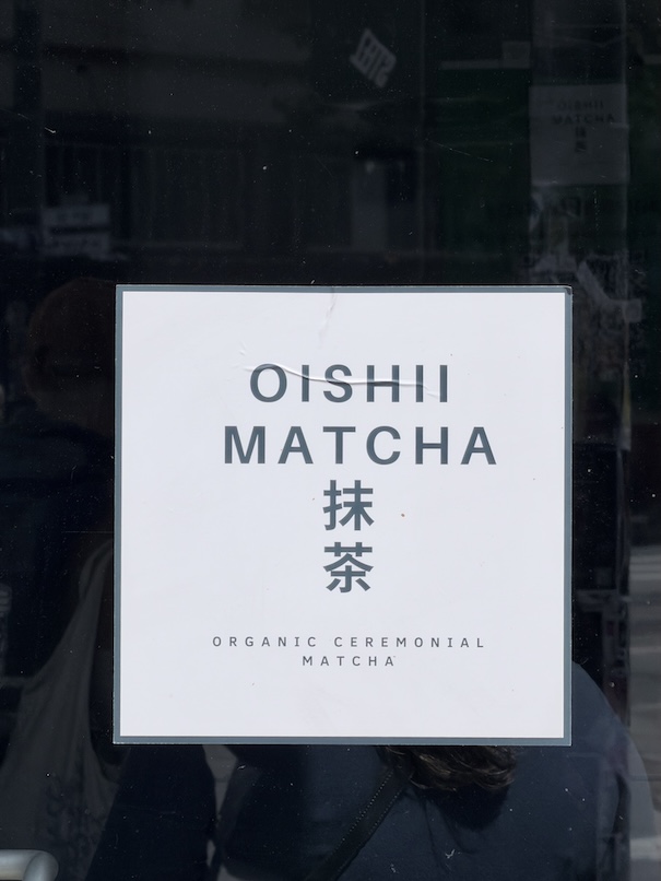 Square white door sign for Oishii Matcha featuring Japanese kanji characters and the text "Organic Ceremonial Matcha"